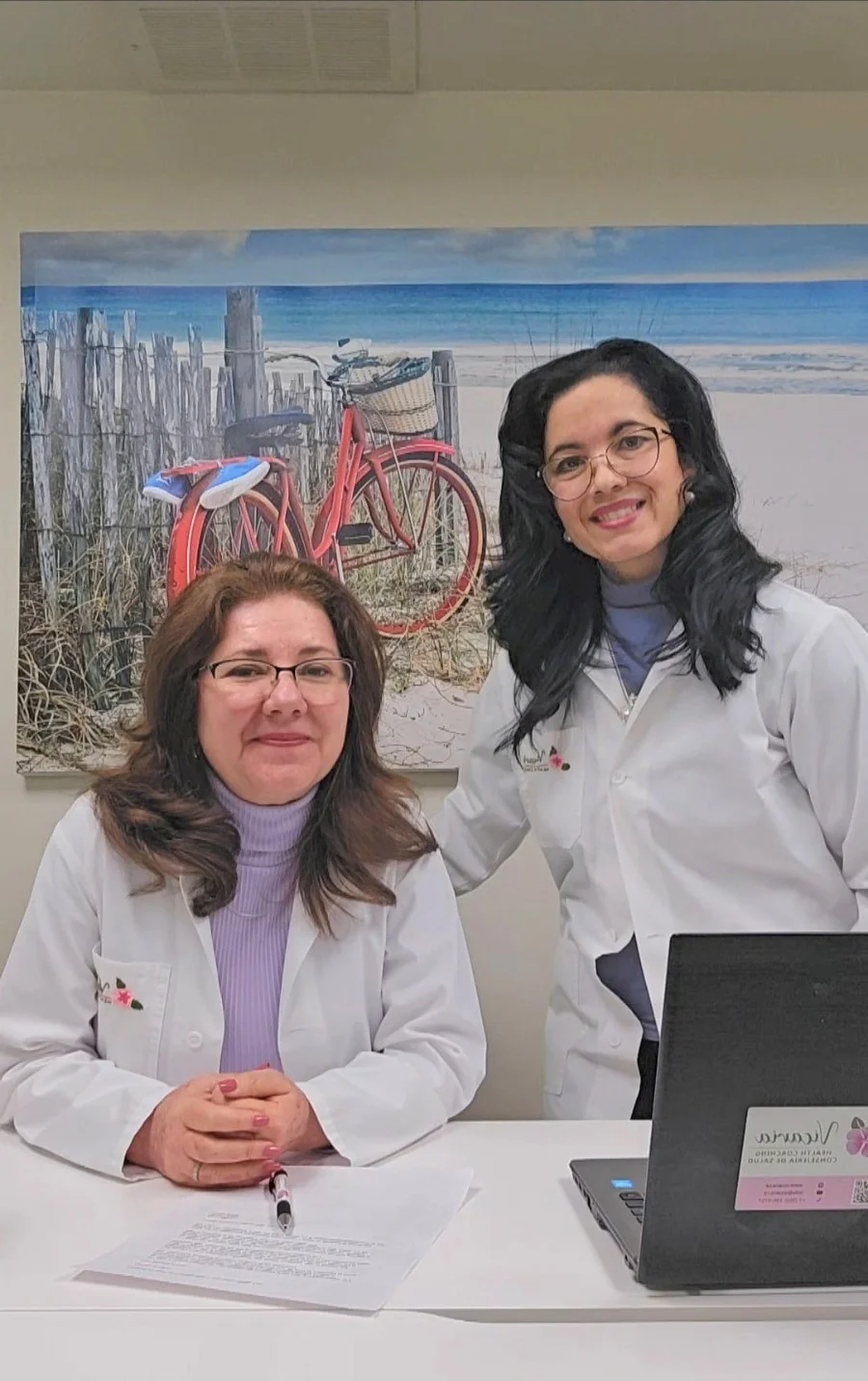 Maurin Casella seated and Yamilet Pina standing at the consultation desk at Vicaria Health in Hamilton